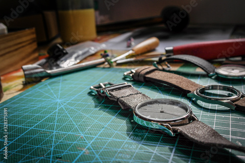 Watches and cases with leather straps in a watchmaker studio on a green cutting board 