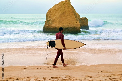 surfista sulla spiaggia dos Três Irmãos situata ad Alvor nell'Oceano Atlantico nella regione dell'Algarve in Portogallo