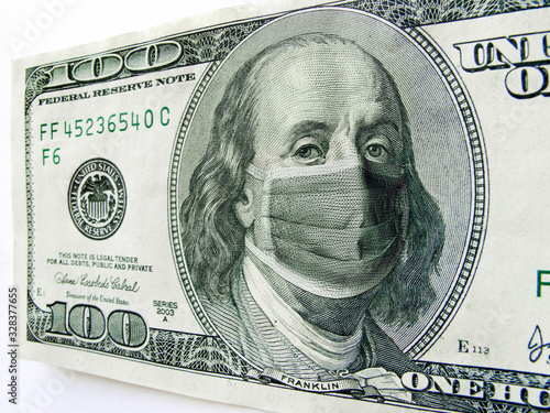 This photo illustration of Ben Franklin wearing a healthcare surgical mask on a one hundred dollar bill illustrates the Coronavirus, international travel, and economic costs