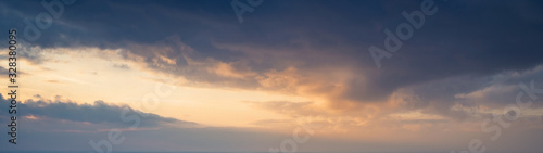 Large panorama of evening sunset sky with dark blue clouds.