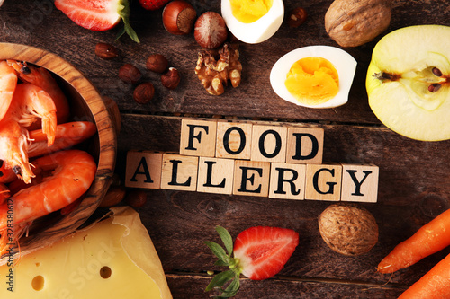 Allergy food concept. Allergy food as almonds, milk, cheese, strawberry, seeds, eggs, peanuts and .crustaceans or shrimps with wooden letter food allergy