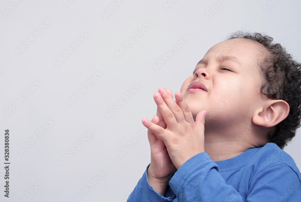 boy praying to God with hands held together with closed eyes boy praying to God with hands held together with closed eyes