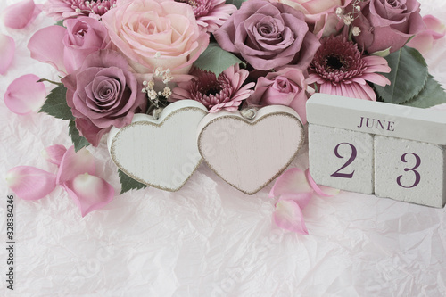 Calendar. June 23th. Wood cube calendar with date of month and day  pink flowers bouquet and two hearts. Greeting card for various holidays. Invitation. Copy space.