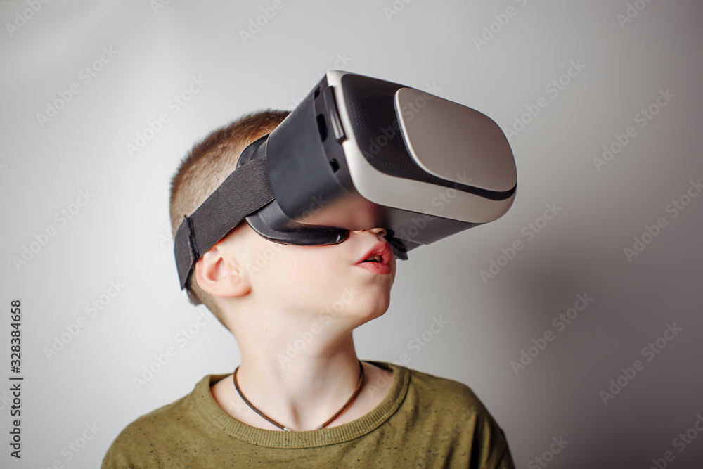 Boy playing mobile game app on device virtual reality glasses on white background. Boy action and using in virtual headset, VR box for use with smart phone. Contemporary technology concept Boy playing mobile game app on device virtual reality glasses on white background. Boy action and using in virtual headset, VR box for use with smart phone. Contemporary technology concept
