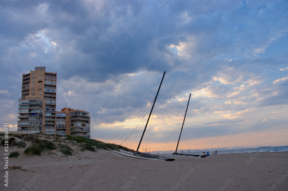 Two sailboats in the sand on the beach on a wonderful afternoon and some coastal buildings. Two sailboats in the sand on the beach on a wonderful afternoon and some coastal buildings.