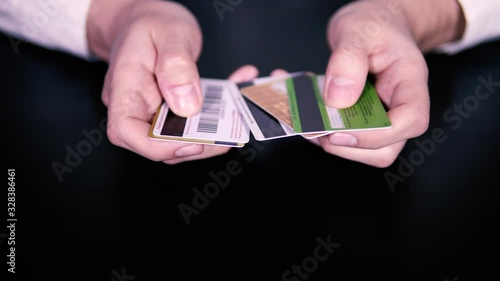 Close up. A man in a white shirt selects a credit card from the available ones. The concept of cashless payments. Refusal of cash. Confusion when choosing a card.