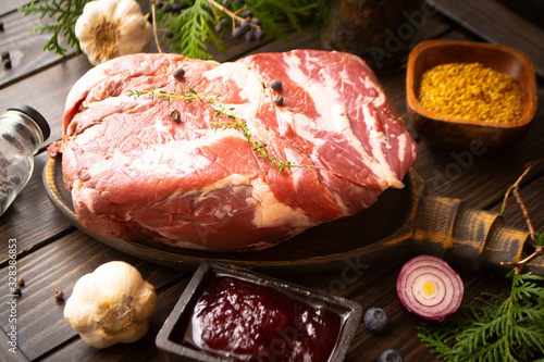 Still life of fresh game boar meat on a wooden table, herbs and wild berries