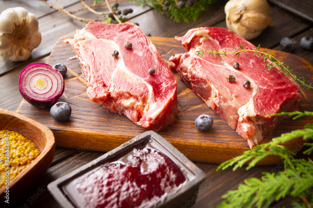 Rare boar filets seasoned with fresh herbs on wooden cutting board