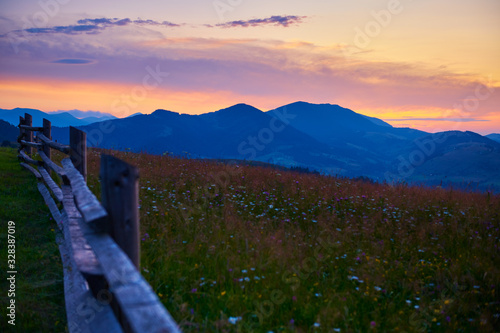sunset and wooden fence along pasture in the ranch, nature, summer landscape in carpathian mountains, spruces on hills, beautiful cloudy sky