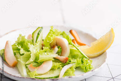 Tableau sur toile plate of salad with seafood and olives on a light background of boards