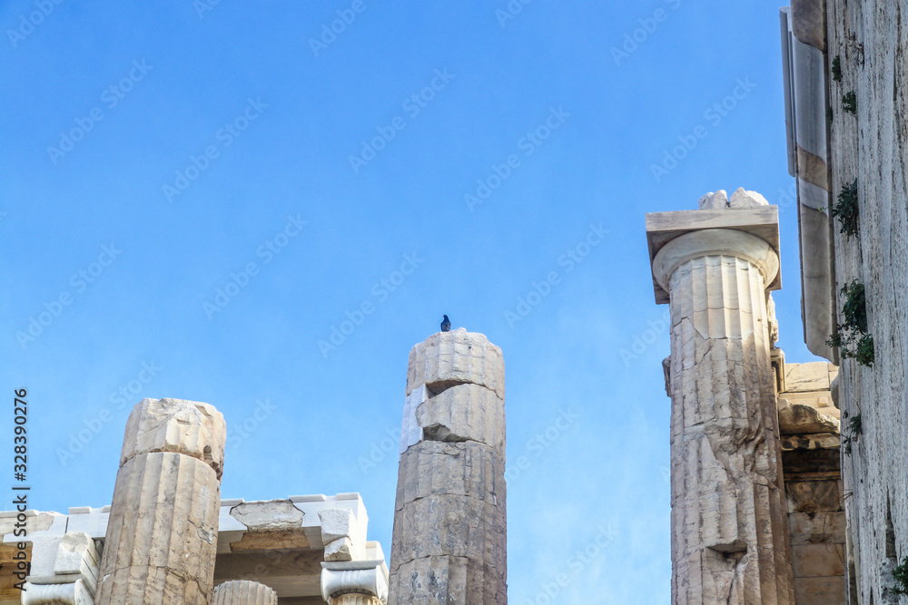 Closeup of reconstructed pillars on Acropolis in Athens Greece with old and new parts fits together - bird perched on top of pillar - room for copy Closeup of reconstructed pillars on Acropolis in Athens Greece with old and new parts fits together - bird perched on top of pillar - room for copy