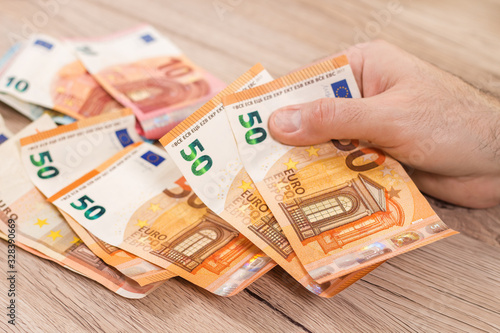 Obraz na płótnie Męska dłoń trzyma kopertę i wyjmuje z niej banknoty Euro o nominałach 50 Euro. w salonie