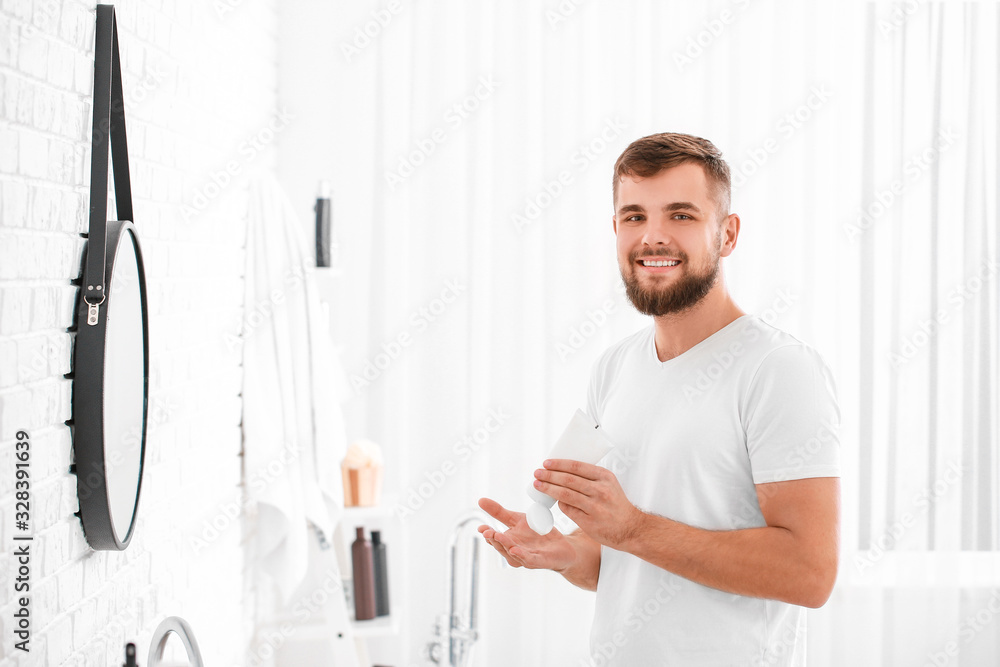 Handsome young man with tube of cream in bathroom