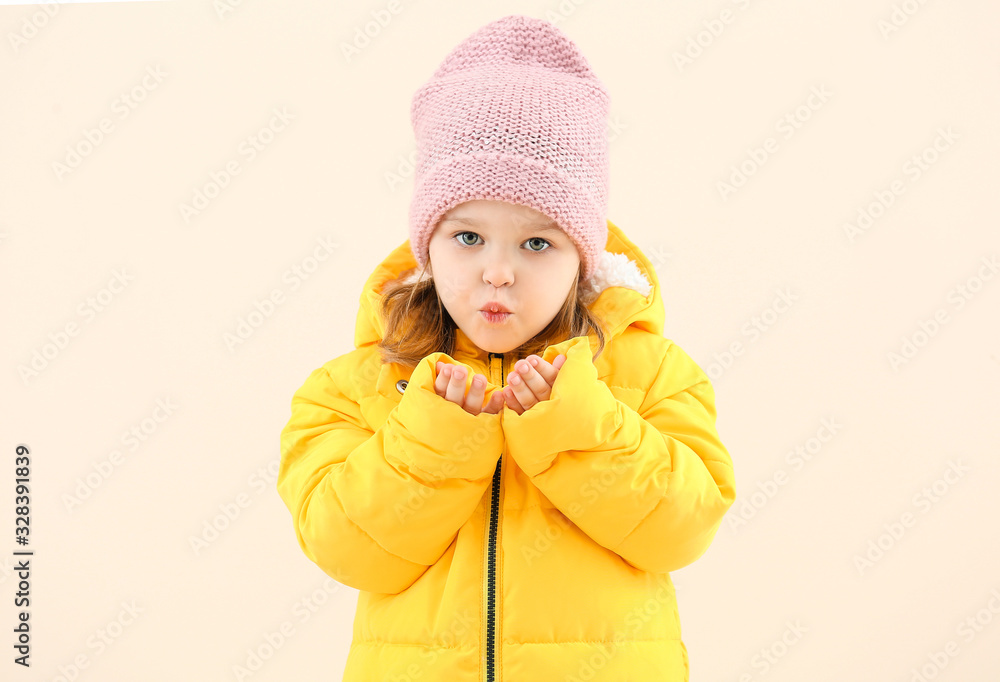 Cute little girl in winter clothes blowing kiss on light background Cute little girl in winter clothes blowing kiss on light background