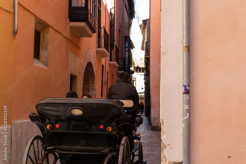 a coach driving in a old thin street in town of Palma de Malorca, Spain