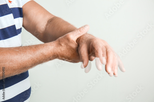 Senior man suffering from Parkinson syndrome on grey background photo