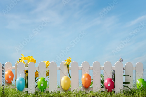 Photography Spring grass and wooden fence with easter eggs and flower on cloudy sky