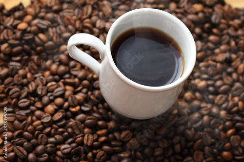 Cup of hot coffee on coffee beans background