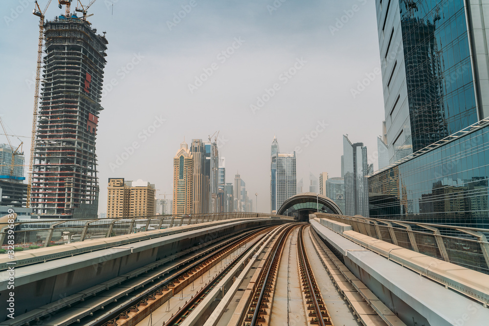 Dubai metro railroad at skyscrapers buildings skyline background.