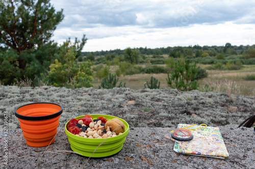 Snack tourist on a hike. Tourist snack in a silicone plate. Map and compass.