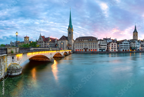 Famous Fraumunster church and Munsterbrucke bridge over river Limmat at sunset in Old Town of Zurich, the largest city in Switzerland