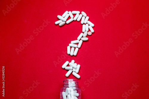 Treatment and healthcare concept. Top view and flat lay of question mark making with different pills, tablets and glass bottle on red background with copy space © Artur Falgowski