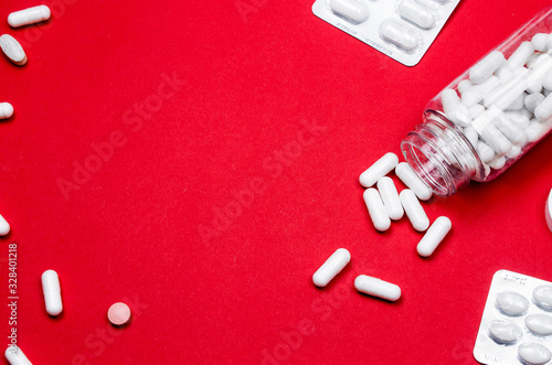 White vitamins and supplements on red background. Concept for a healthy dietary supplementation. Close up. © Artur Falgowski