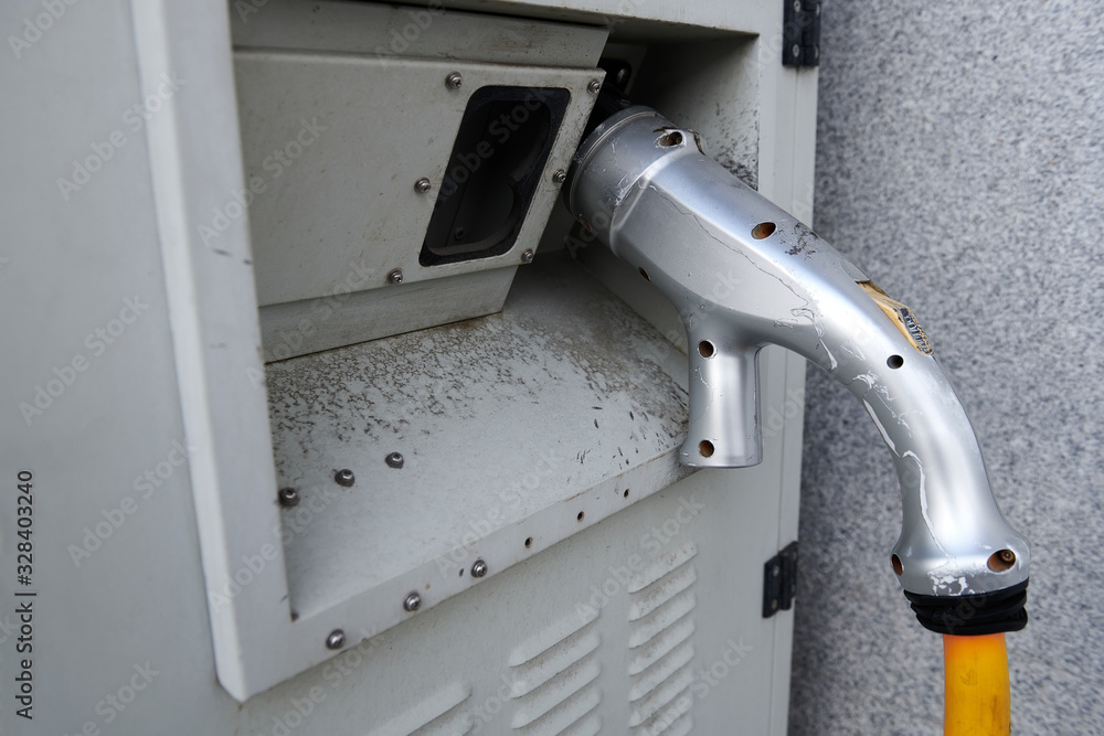 An old silver aluminium plug-in connector at the electric station. For ecological transportation. Closeup. An old silver aluminium plug-in connector at the electric station. For ecological transportation. Closeup.