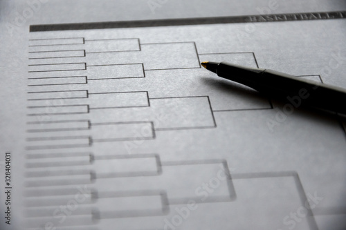 Blank basketball bracket grid on white paper with pen laying on top