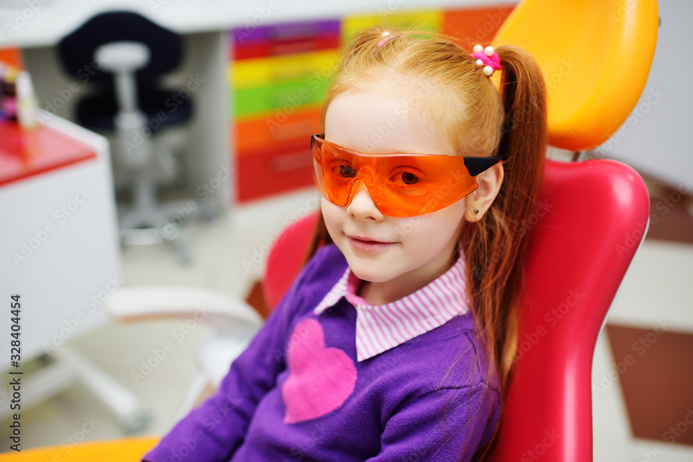 baby girl in dental glasses smiling sitting in dental chair. baby girl in dental glasses smiling sitting in dental chair.