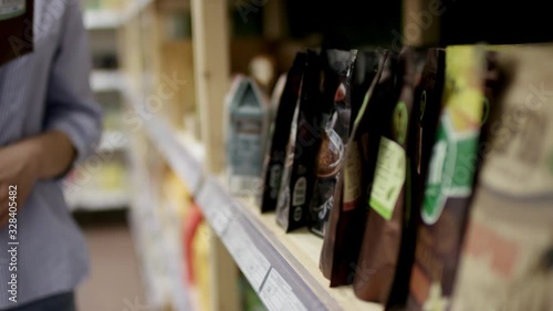 Close up view of customer hands taking a doy-packed good from shelf in supermarket