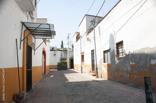Lonely alley in the picturesque rustic rustic town of Asunción in Mexico City with the typical facades of houses painted in yellow and white