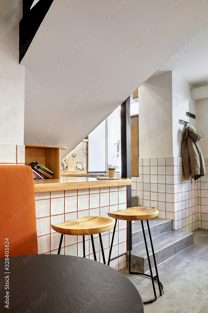Fototapeta premium Stylish. Modern interior of cafe.Authentic style with element of loft.Round black and white tables,chairs and orange sofa..White tiles with orange lines.Orange,white and grey colors.