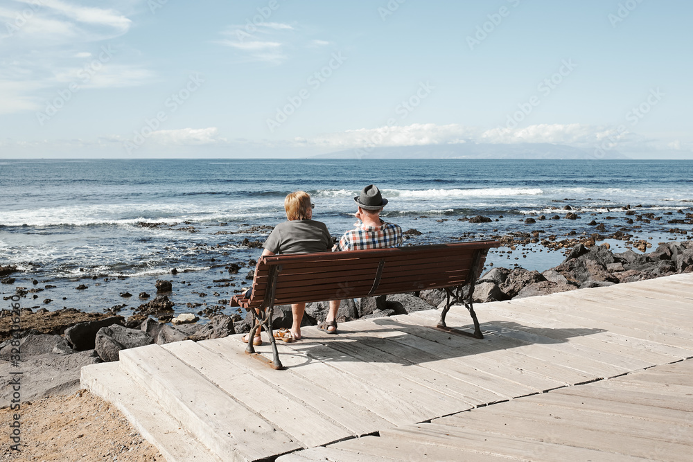 Elderly couple of tourists at a sea resort on a sunny summer day. Tourism and travel, vacation. Tropical island Tenerife landscape.