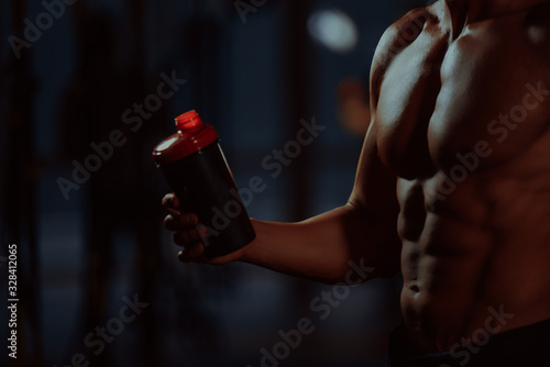 Lifestyle portrait of handsome muscular man drinking water in the gym. Young man drinks water in the gym. another view close