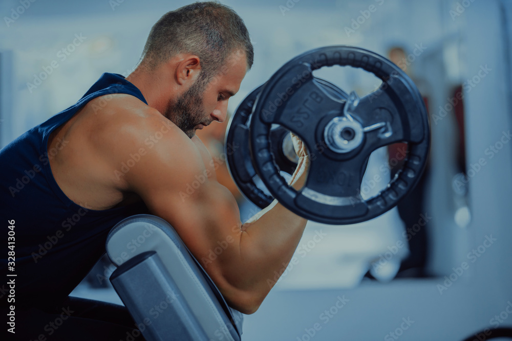 Muscular man working out in gym doing exercises for biceps, strong male Muscular man working out in gym doing exercises for biceps, strong male