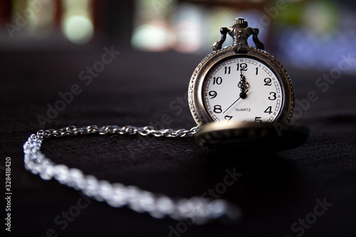 Stylish pocket watch on black surface and out of focus background
