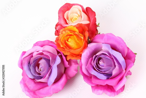 Artificial violet and red roses on white background