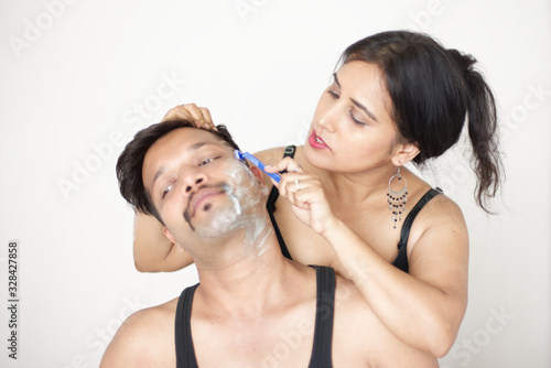 Attractive Indian Bengali brunette couple seductive foreplay in black dress in a white bedroom while the girl is shaving the man in a seductive way. Indian lifestyle 