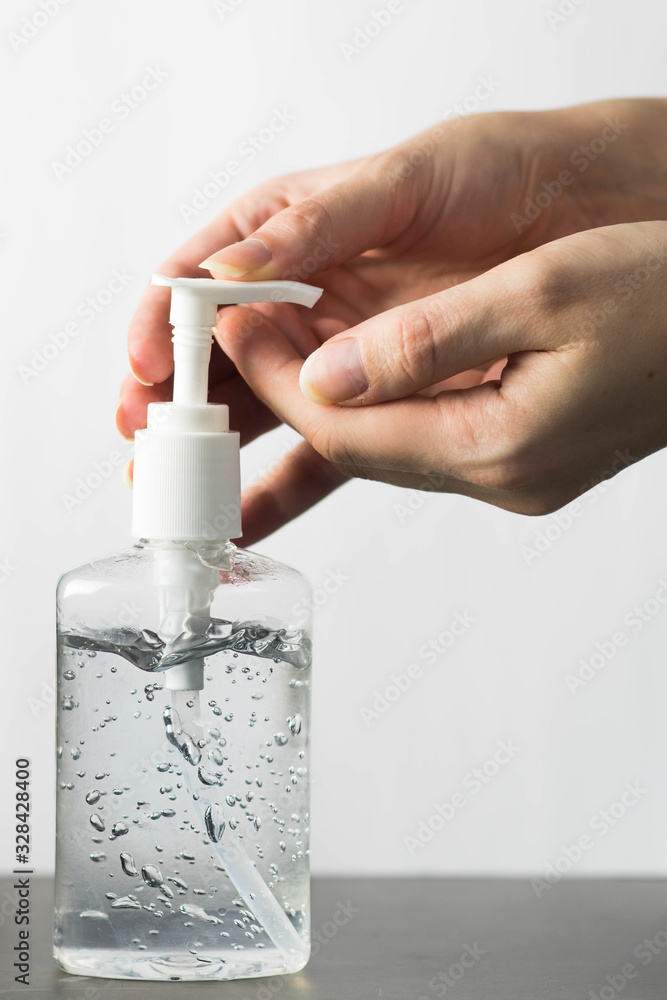 Caucasian woman hands using bottle of alcohol hand sanitizer, hand disinfectant on white background. Woman preventing coronavirus infection during sars-cov-2, covid-19 epidemic in Europe.