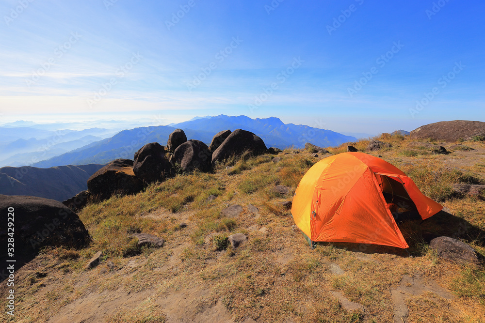 Orange tent on a high hill in the morning