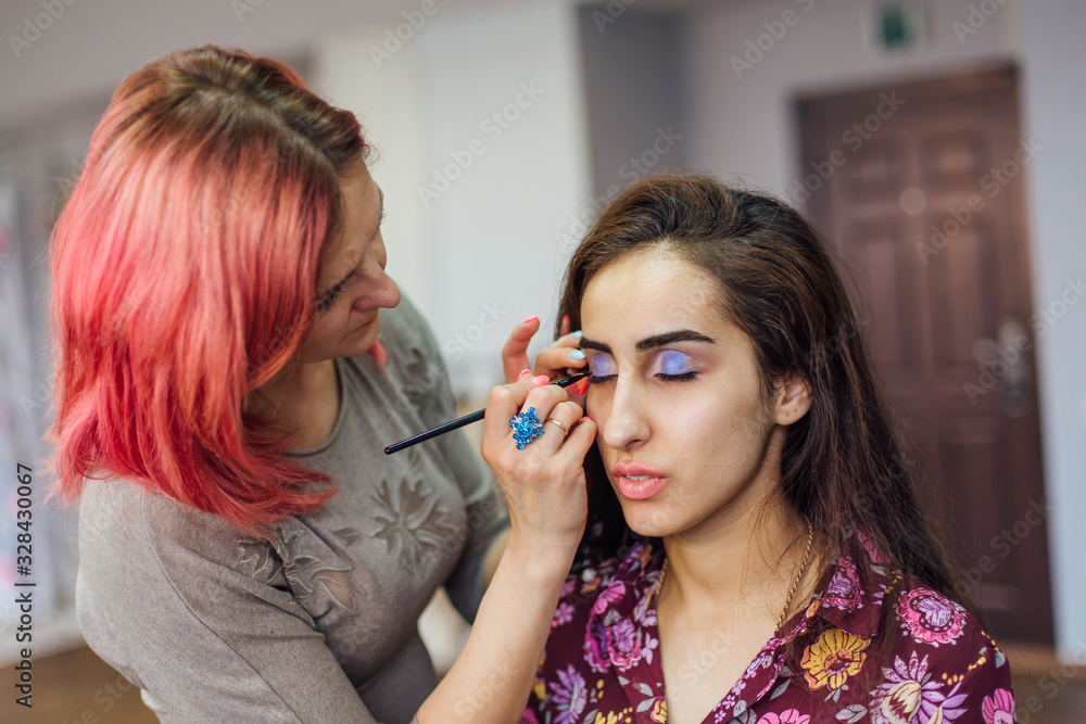 Make-up artist working with model in studio. Make-up artist working with model in studio.