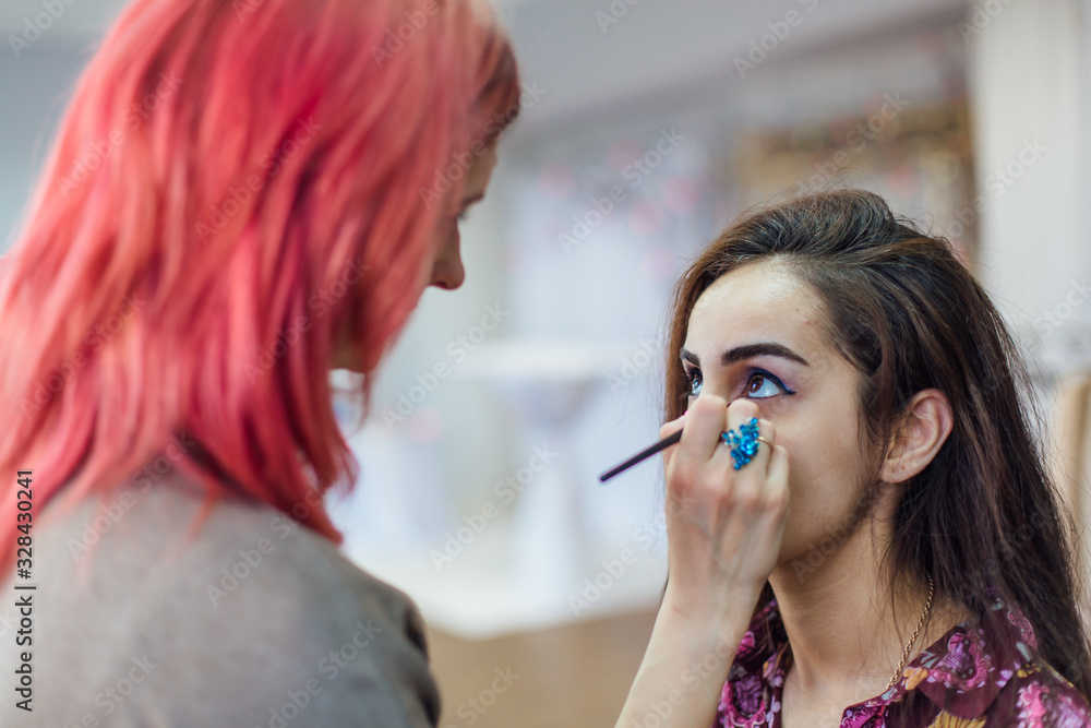 Make-up artist working with model in studio.
