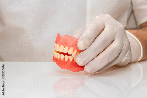 False teeth prosthesis. Doctor Dentist. A dental technician holds a false jaw in his hand with a medical glove.