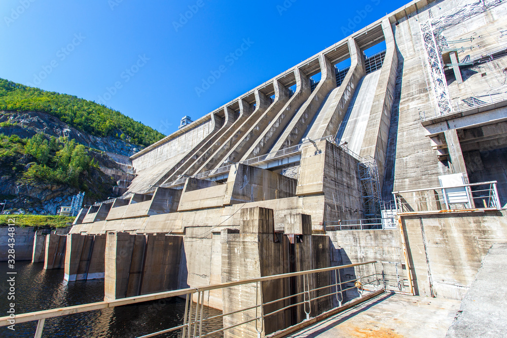 Industrial photography. The main building with turbines of the Zeya hydroelectric station on the background of a concrete dam.