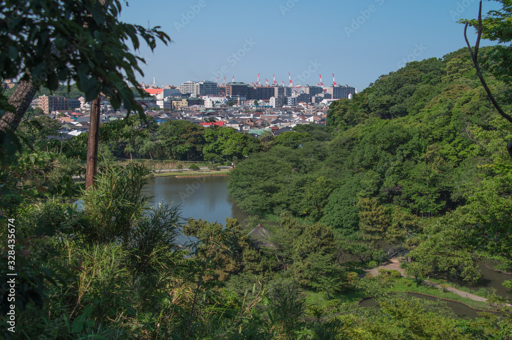view from the top of hill. Japanese garden and city buildings.