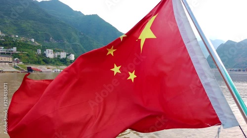 Red chinese national flag fluutering on the mast on the passenger tourist boat leaving Badong town on the trip to the Shennong Xi Stream, Yangtze River tributary, China photo