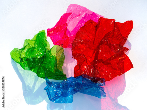 Fotografi Thin sheet of multi coloured cellophane with shiny crumpled surface texture on w