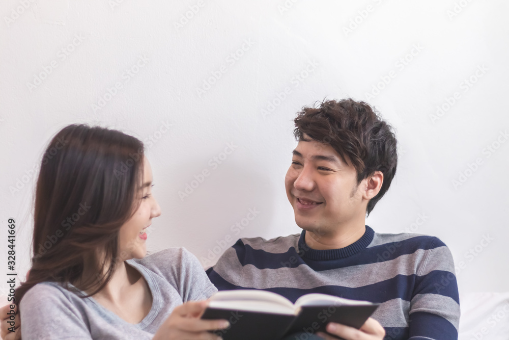 Lovely attractive young Asian couple man and woman with happy smile and reading book in romantic moment. Warm heart marriage and lover bonding and relationship. Husband and wife in love photo concept Lovely attractive young Asian couple man and woman with happy smile and reading book in romantic moment. Warm heart marriage and lover bonding and relationship. Husband and wife in love photo concept