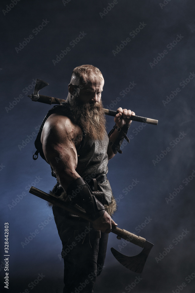 Fotografie Medieval warrior berserk Viking with axes attacks enemy